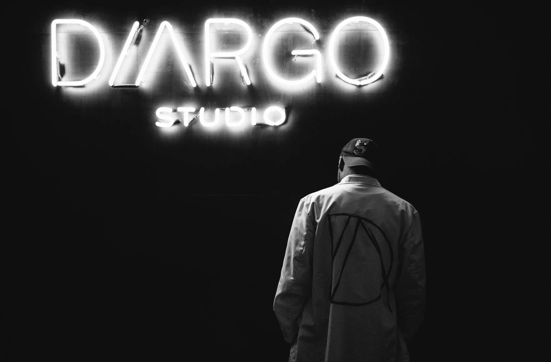 Het neonbord met DIARGO STUDIO in het salon, met een medewerker in witte jas ervoor.